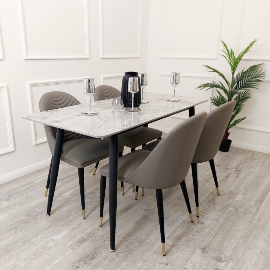 The Titus Dining Table is a real statement dining set, boasting a 140cm tabletop marble effect veneer, sleek black legs, leather chairs, full luxury dining set